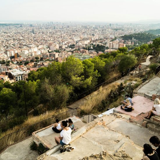 View from Bunkers del Carmel with people sitting on the old concrete terraces, looking out over Barcelona’s skyline