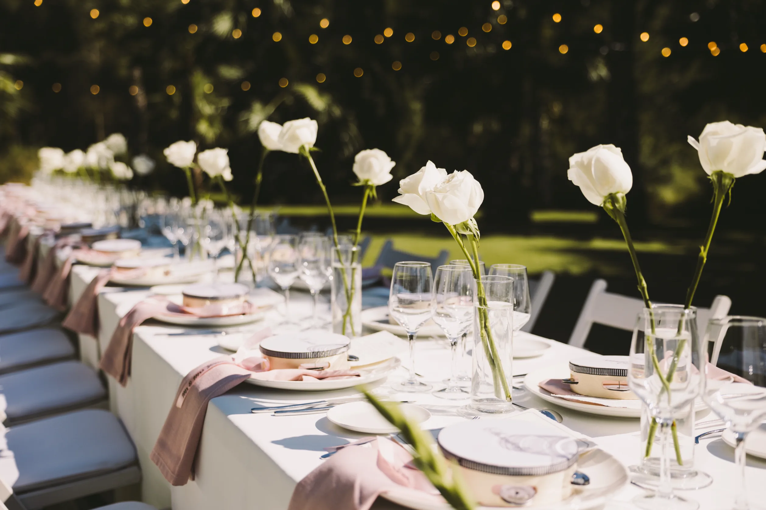 Mesa de boda decorada con rosas blancas y guirnaldas de luces en Casa Nova Estate