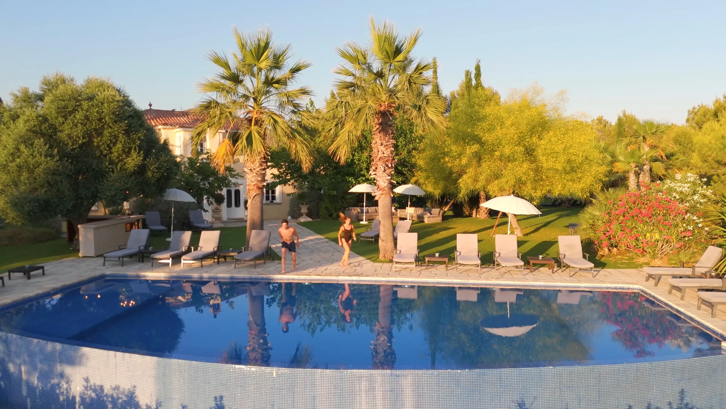 Hogars a la piscina de Casa Nova Estate, envoltats de palmeres i gandules