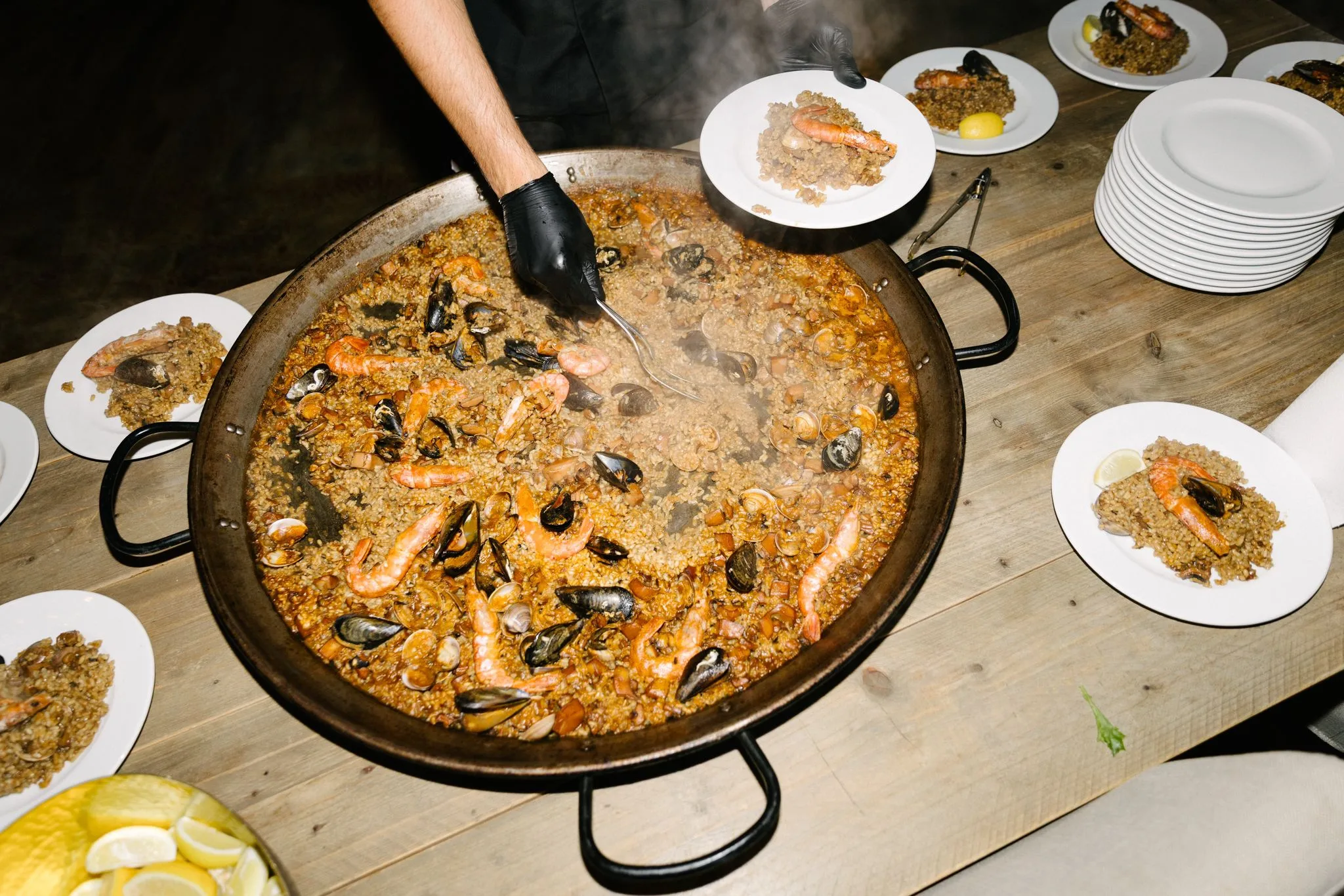 Chef sirviendo paella de mariscos con mejillones y langostinos de la sartén