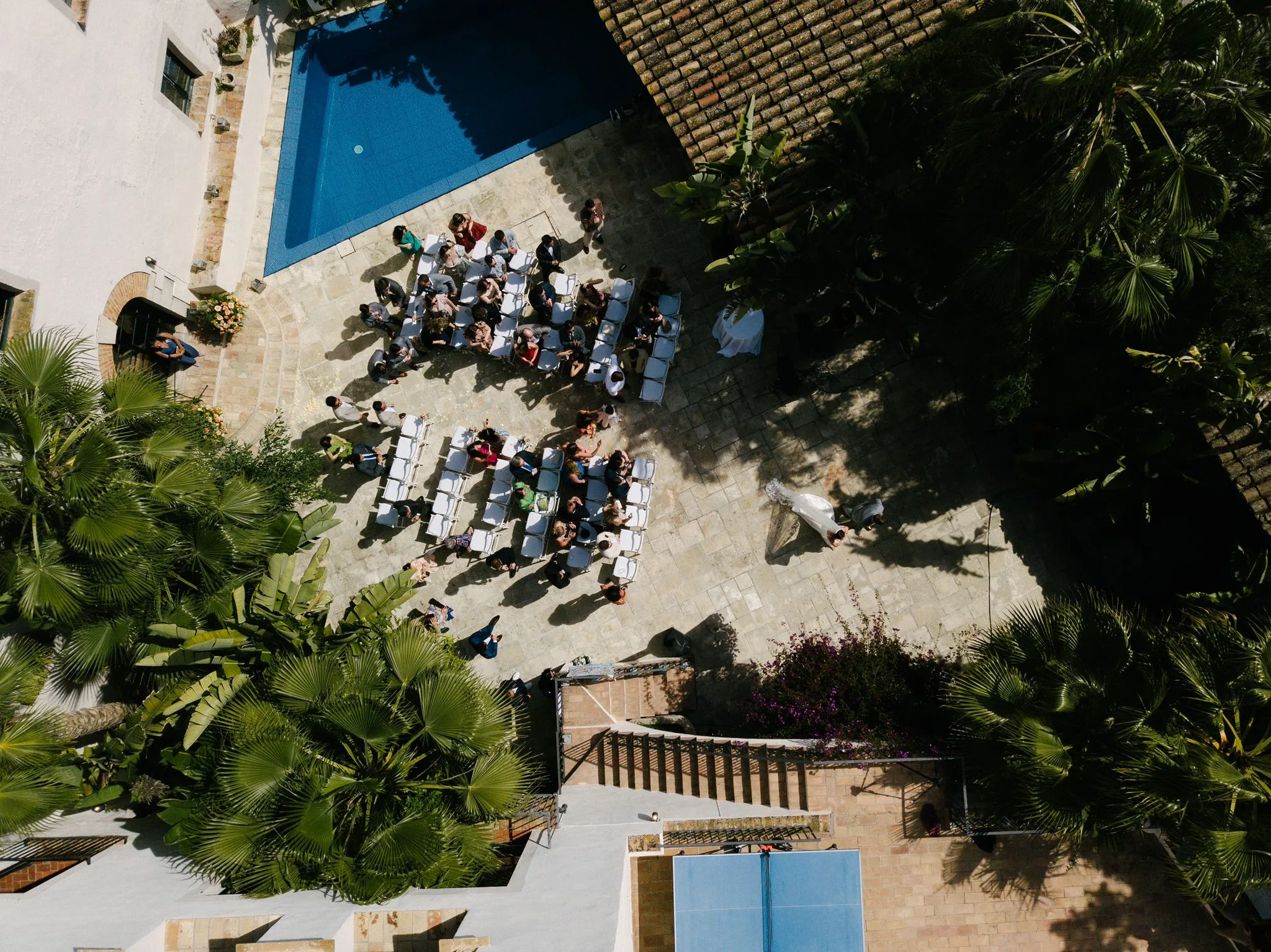 Vista aérea de una recepción de boda dispuesta en la terraza de la villa junto a la piscina