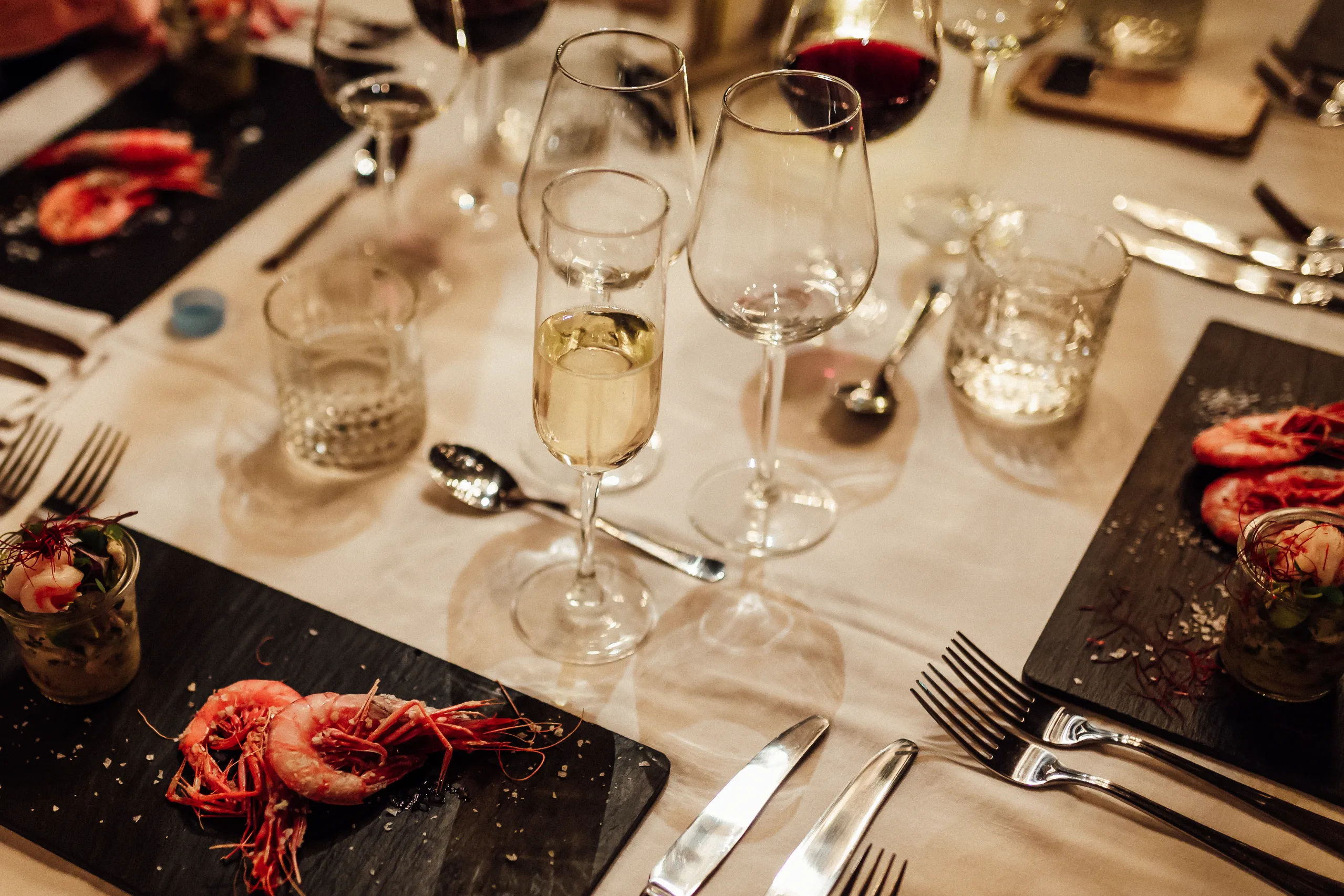 Copas de vino y cubiertos en una mesa puesta para cenar