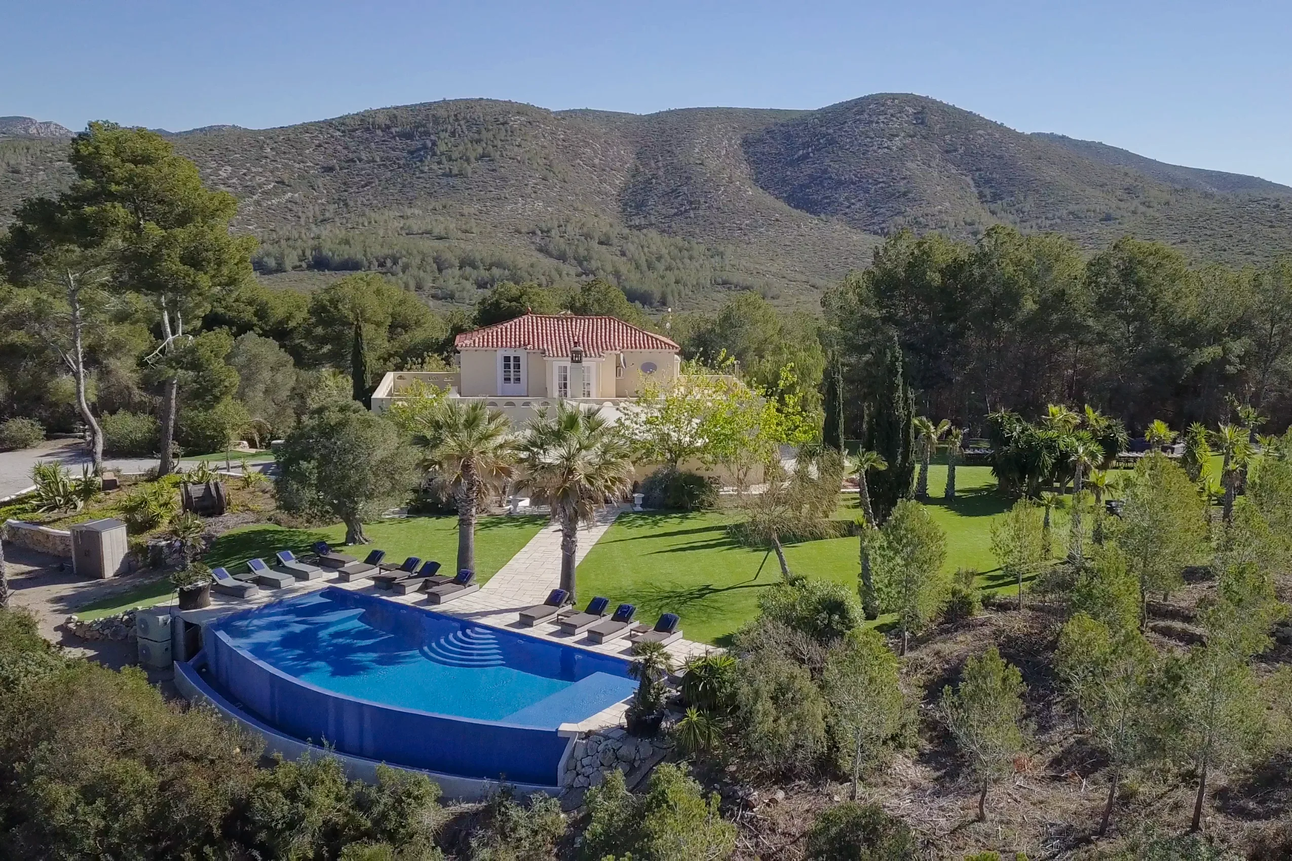 Finca Casa Nova vista desde arriba, con su piscina, sus jardines y las colinas al fondo