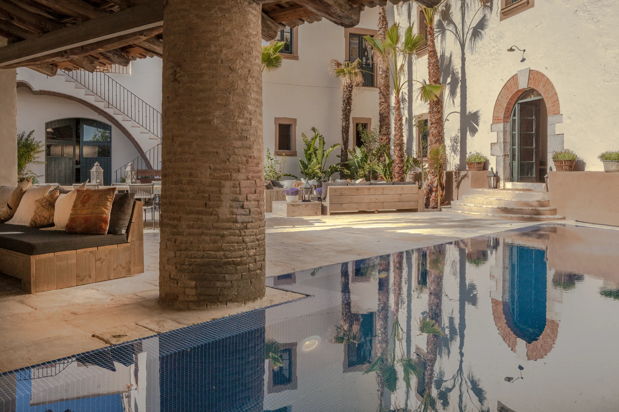 Masia Victòria reflectida a la piscina al costat de la terrassa de pedra