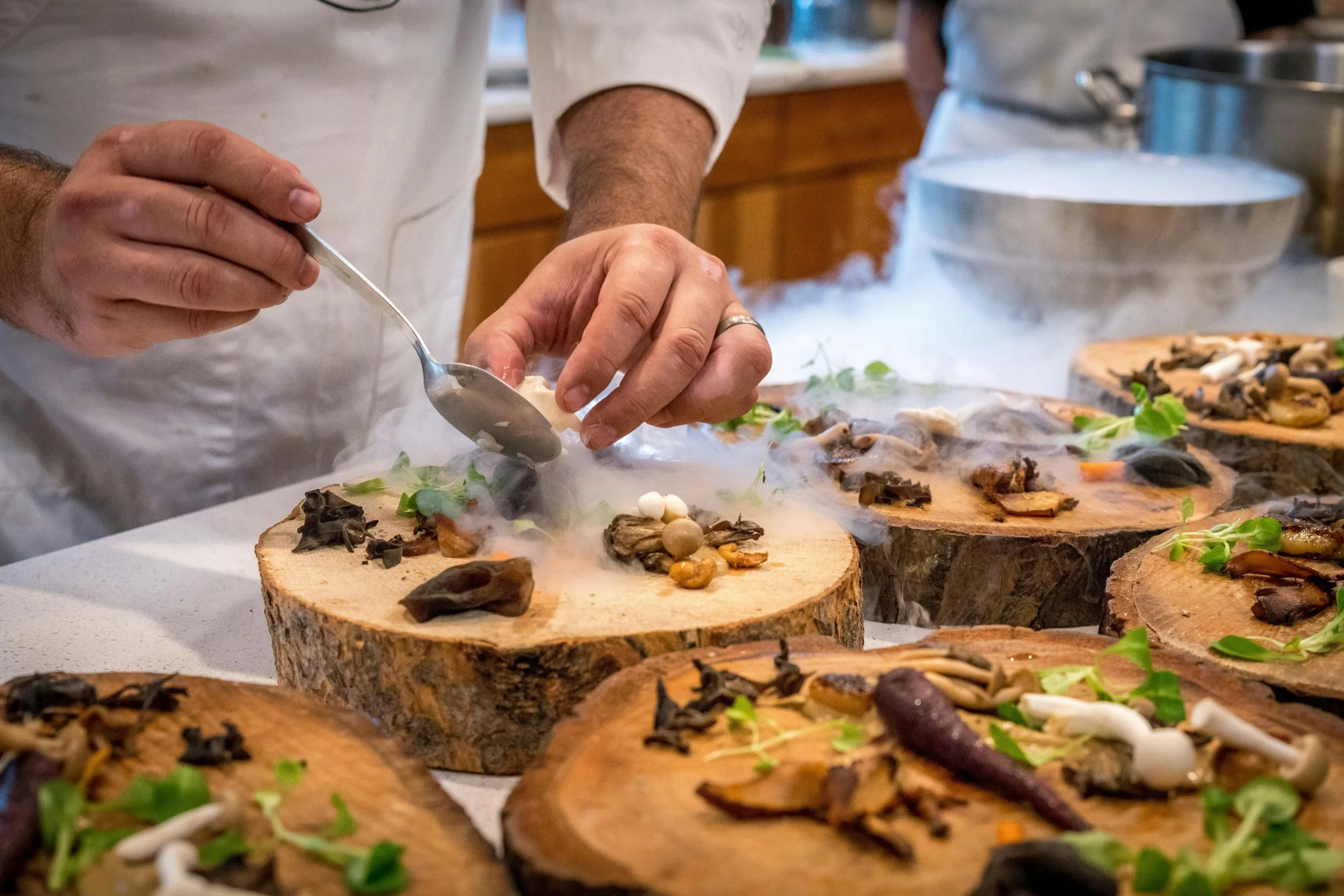 Xef emplatant un plat fumat en una taula de servir de fusta