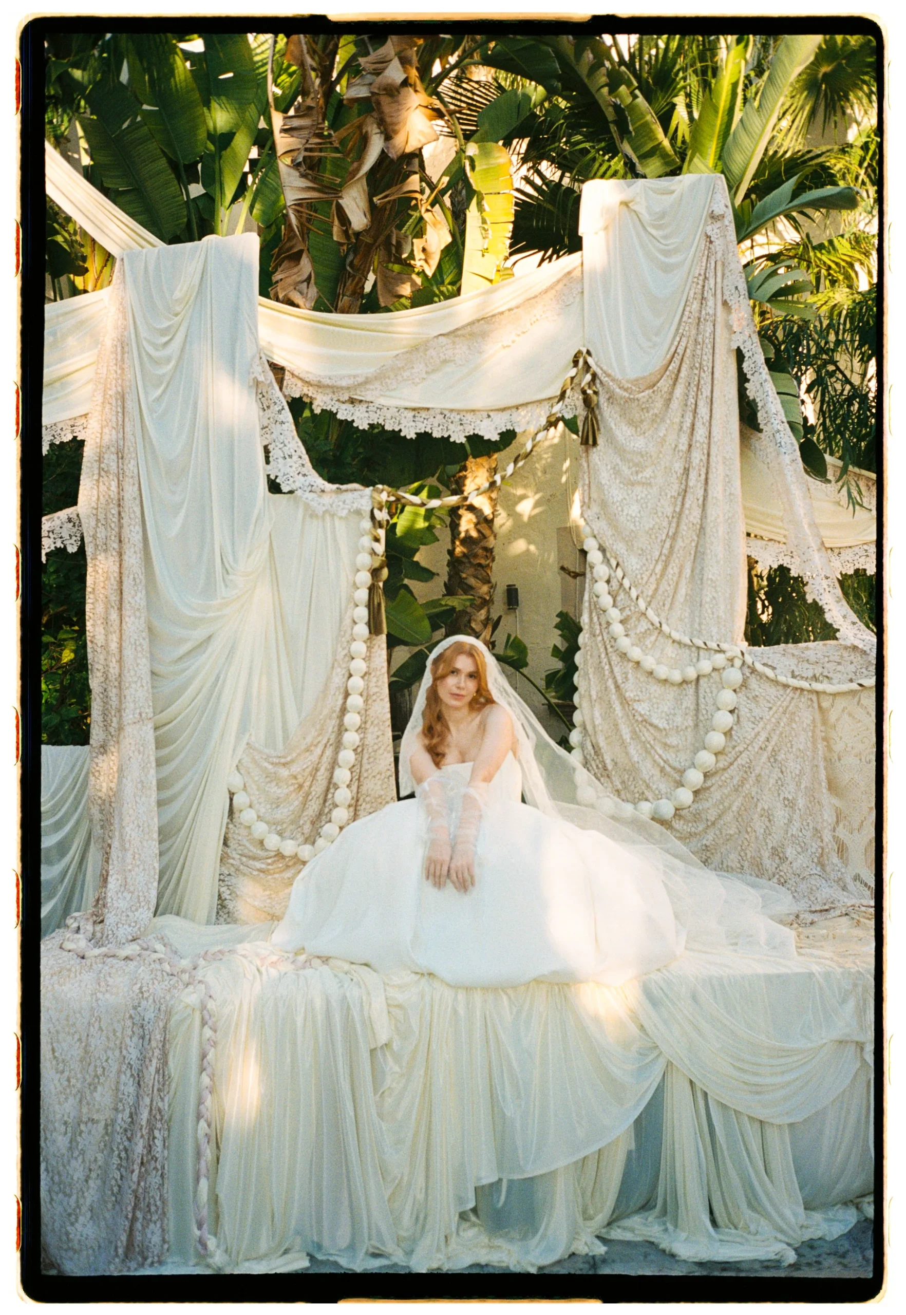 Bride in her gown beneath draped fabric and fairy lights