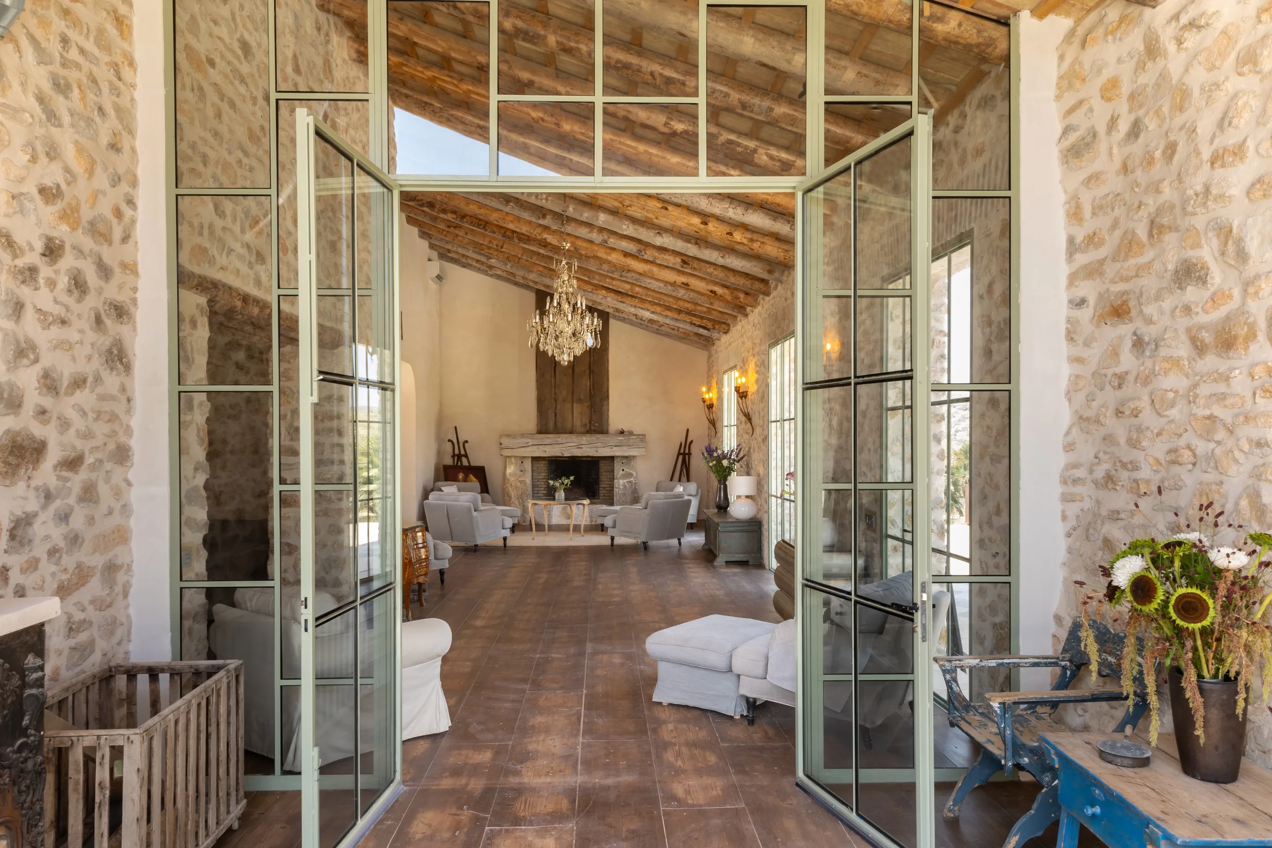 Living room at Mansion Los Naranjos with exposed beams, a chandelier and a stone fireplace